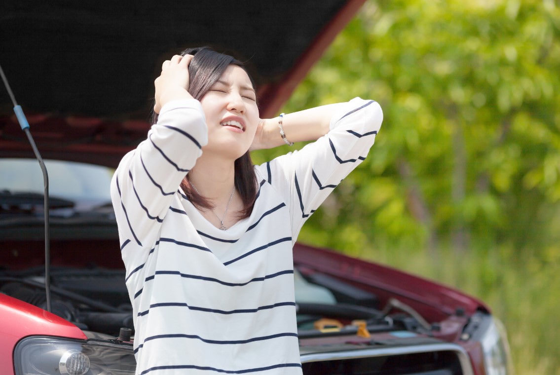 車のトラブルで頭を抱える女性