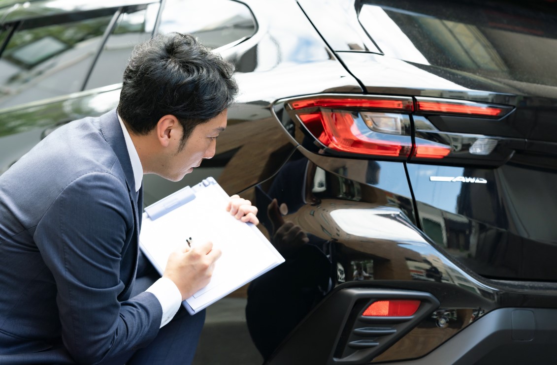 黒い車の角を査定するビジネスマン