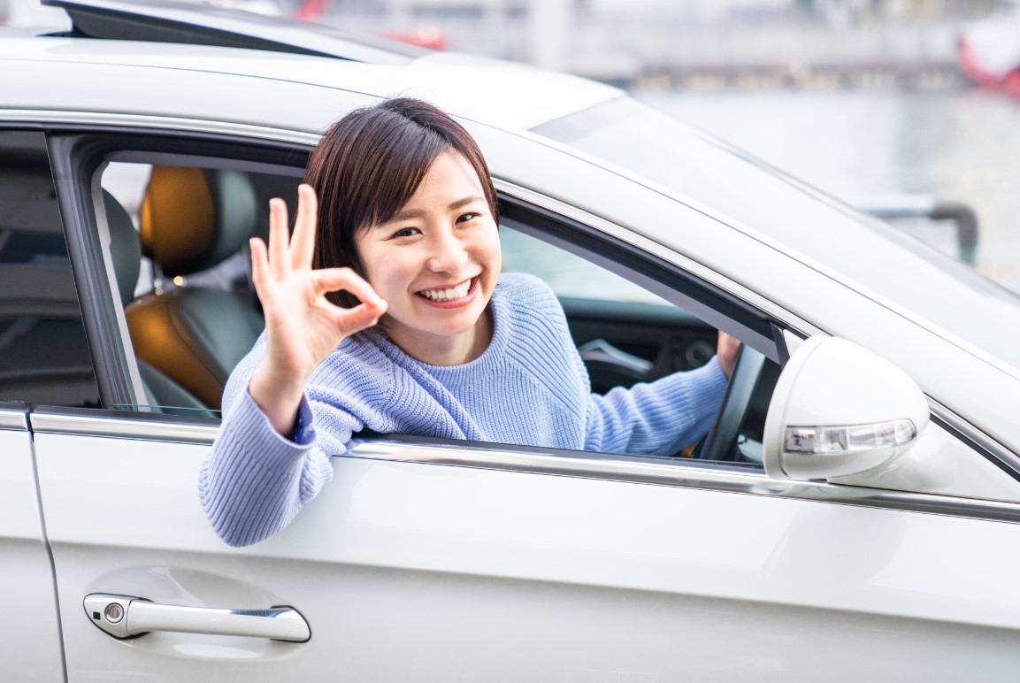 車に乗りながらOKポーズをする女性