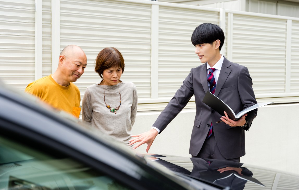 夫婦に車の説明をする男性ビジネスマン